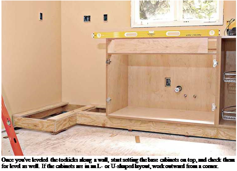 Подпись: Once you've leveled the toekicks along a wall, start setting the base cabinets on top, and check them for level as well. If the cabinets are in an L- or U-shaped layout, work outward from a corner. 