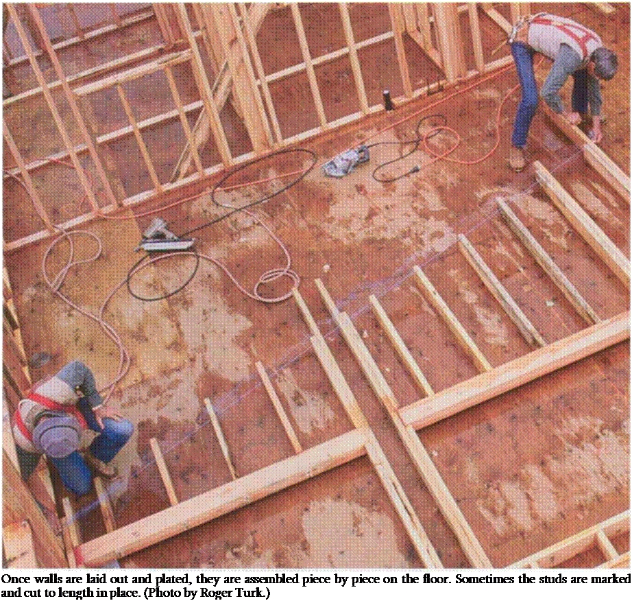 Подпись: Once walls are laid out and plated, they are assembled piece by piece on the floor. Sometimes the studs are marked and cut to length in place. (Photo by Roger Turk.) 