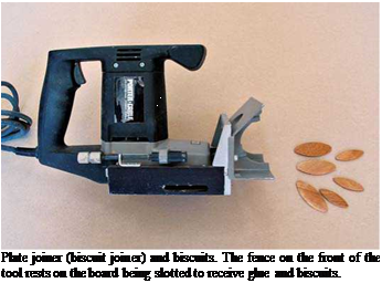 Подпись: Plate joiner (biscuit joiner) and biscuits. The fence on the front of the tool rests on the board being slotted to receive glue and biscuits. 
