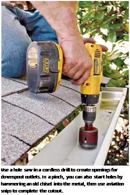 Подпись: Use a hole saw in a cordless drill to create openings for downspout outlets. In a pinch, you can also start holes by hammering an old chisel into the metal, then use aviation snips to complete the cutout. 